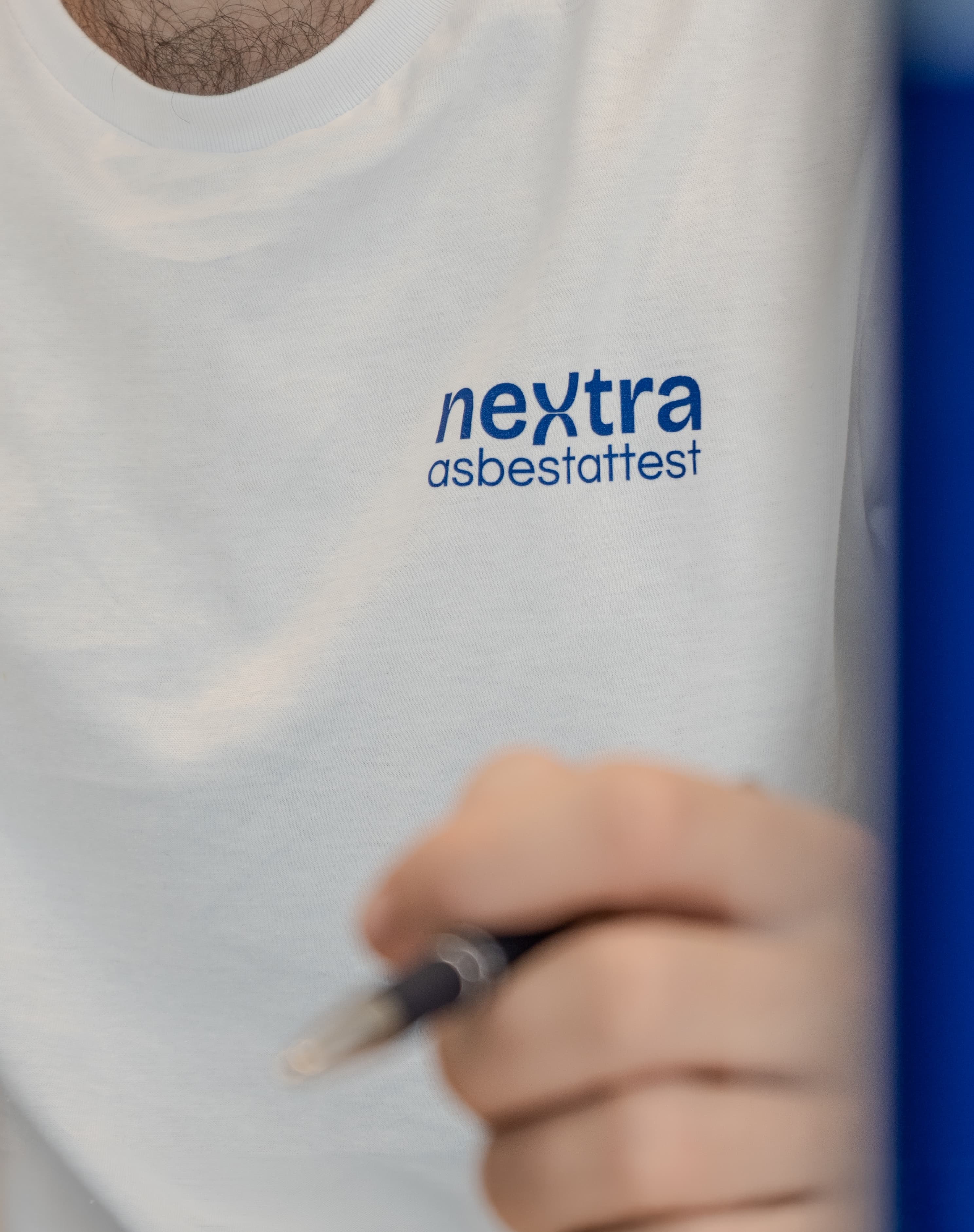 Detail van het Nextra asbestattest-logo op werkkleding